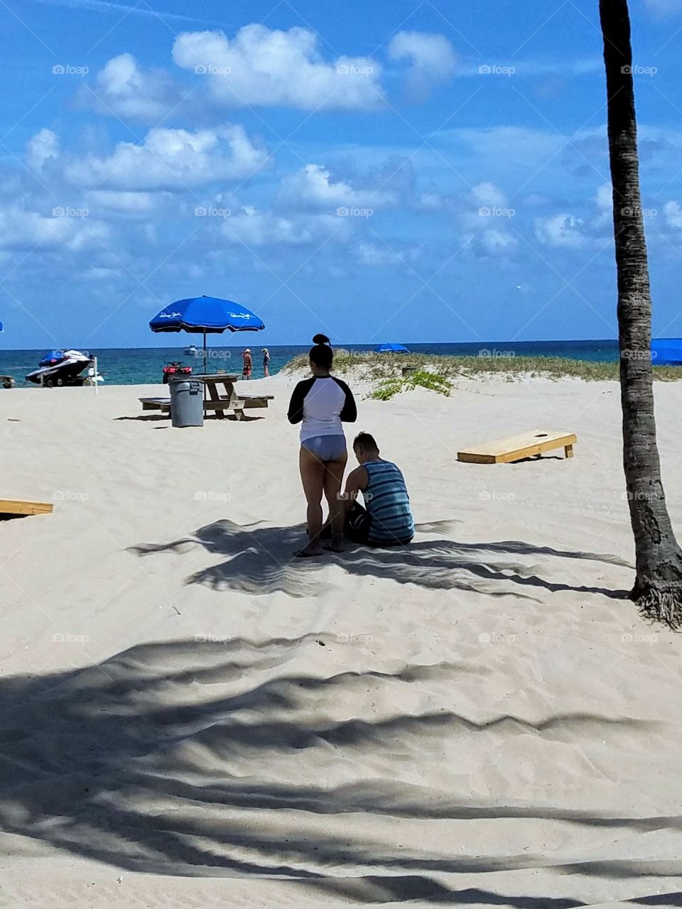Summer Activities in USA. Enjoying the beach day but hott sand means sitting in shade. These 2 are sitting on  shade spot😁