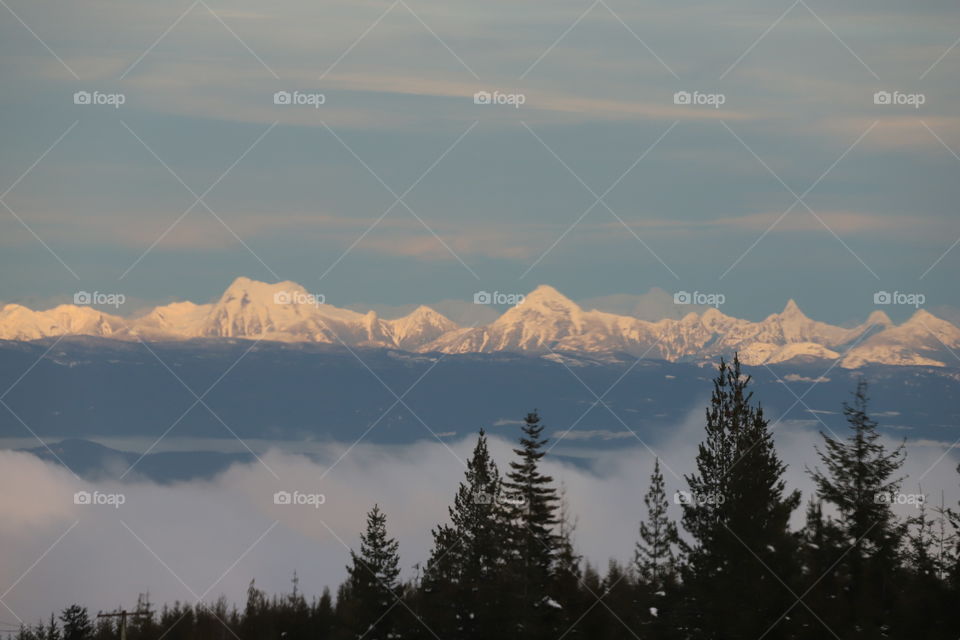 Mountain covered with snow above the fog 