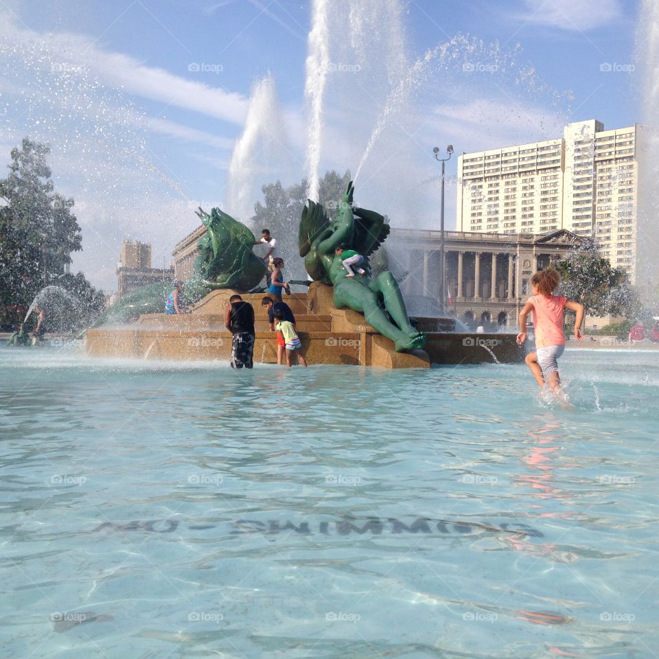 Kids Playing In Fountain. Children playing in Philadelphia's Logan Circle fountain with No Swimming warning visible below the water