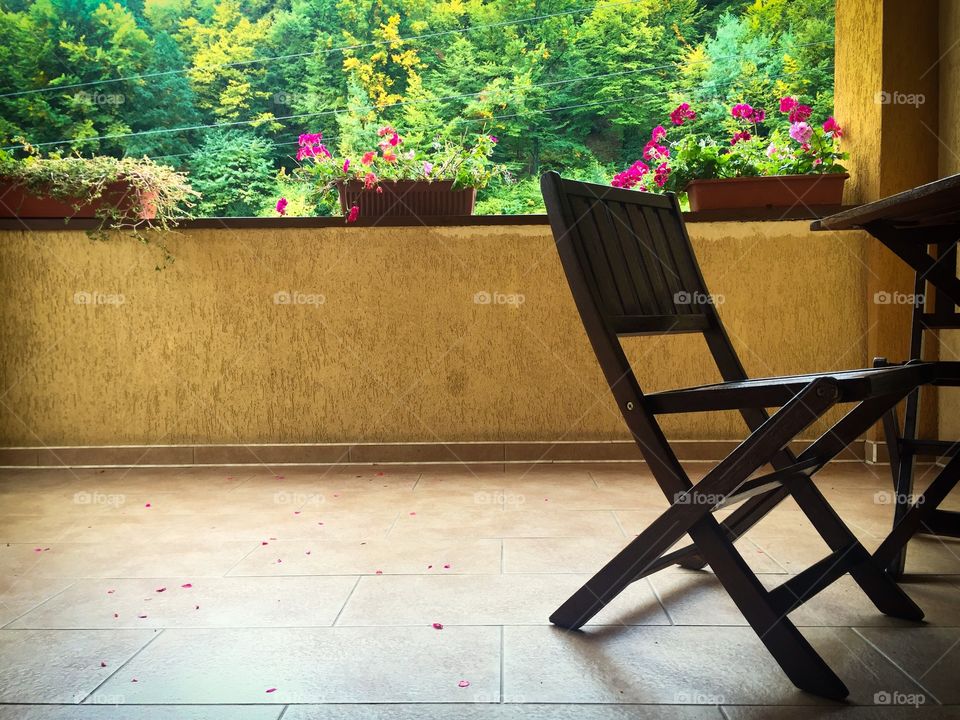 Single wooden chair on the terrace with flowers and forest in the background 