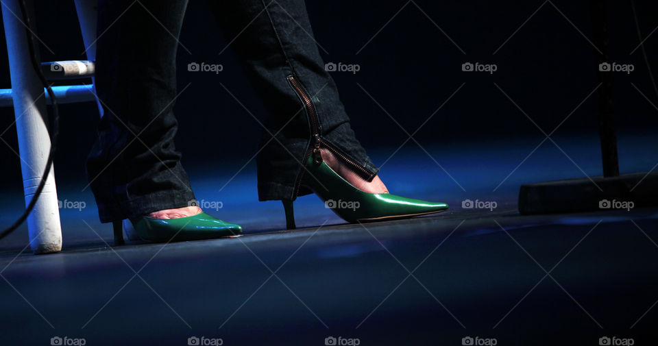 Woman feet with green high heels on stage