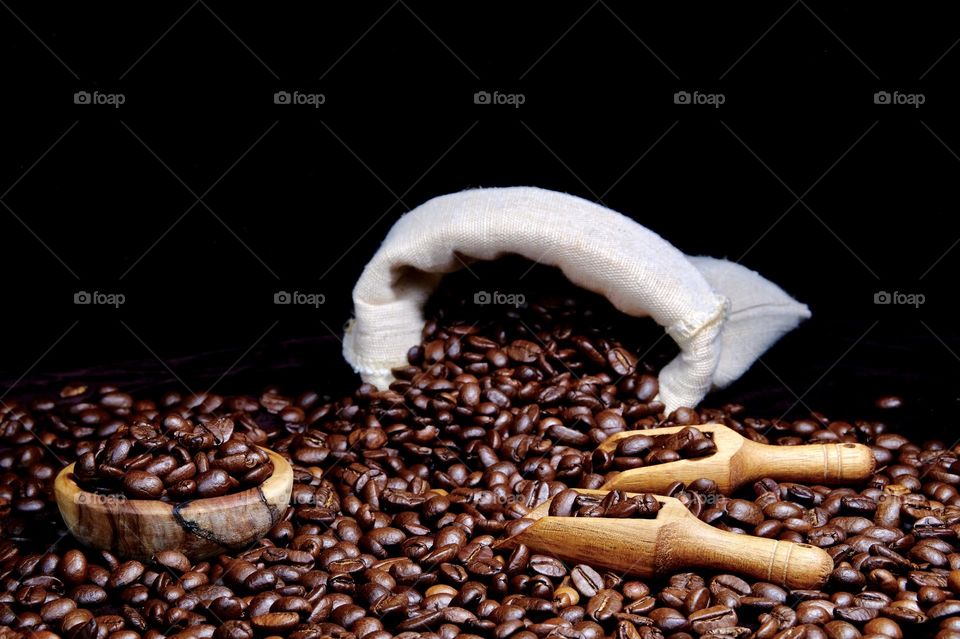 Low angle view of spilled roasted coffee beans from burlap sack.