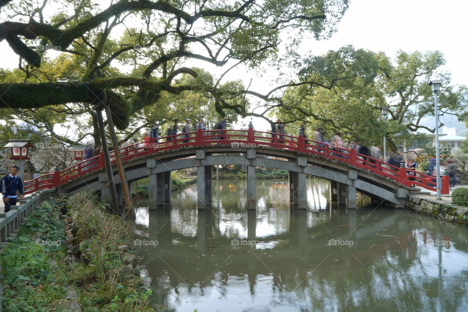 People walking across Japanese wooden bridge 