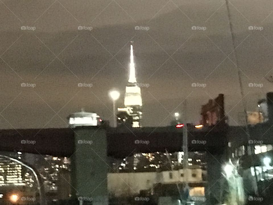 The Pulaski Bridge in Long Island City, Queens, NY at nighttime with the illuminated Empire State Building and indications of the Manhattan skyline in the far distance at the horizon. 2019. Hypnotic Productions