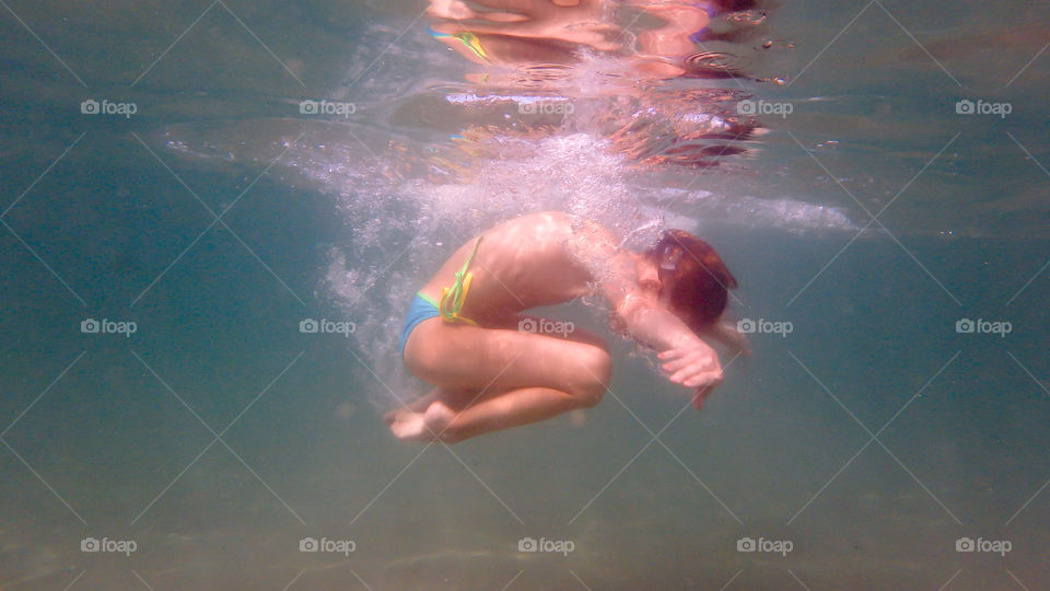 young girl underwater making circles, diving, sea