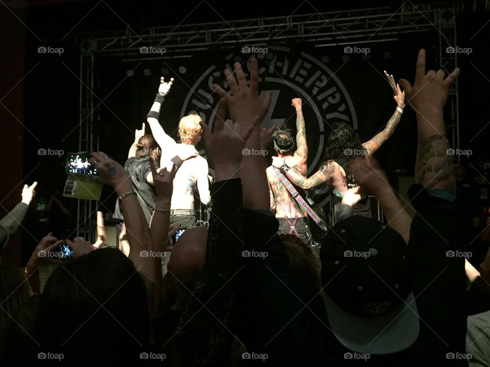 Crowd of fans with their hands up watching a rock band