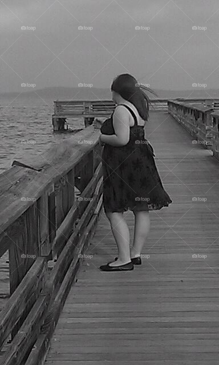 Woman looking across the water from a pier 