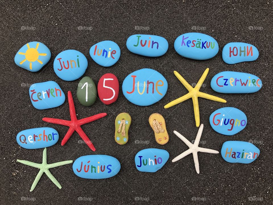 15 June, calendar date with multicolored stones and starfishes over black volcanic sand