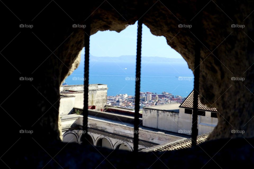 City and sea view from a broken wall with metal bars