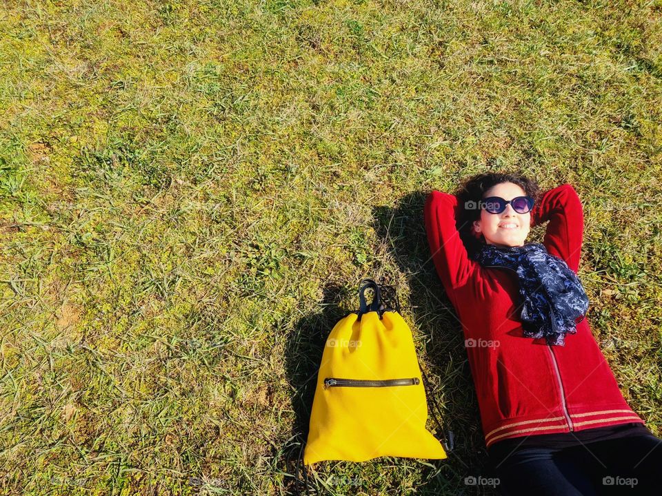 photo from above of a smiling woman lying on the grass