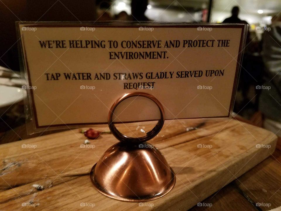 A notice at a restaurant in Alameda, California informing guests that tap water and straws must be requested directly.