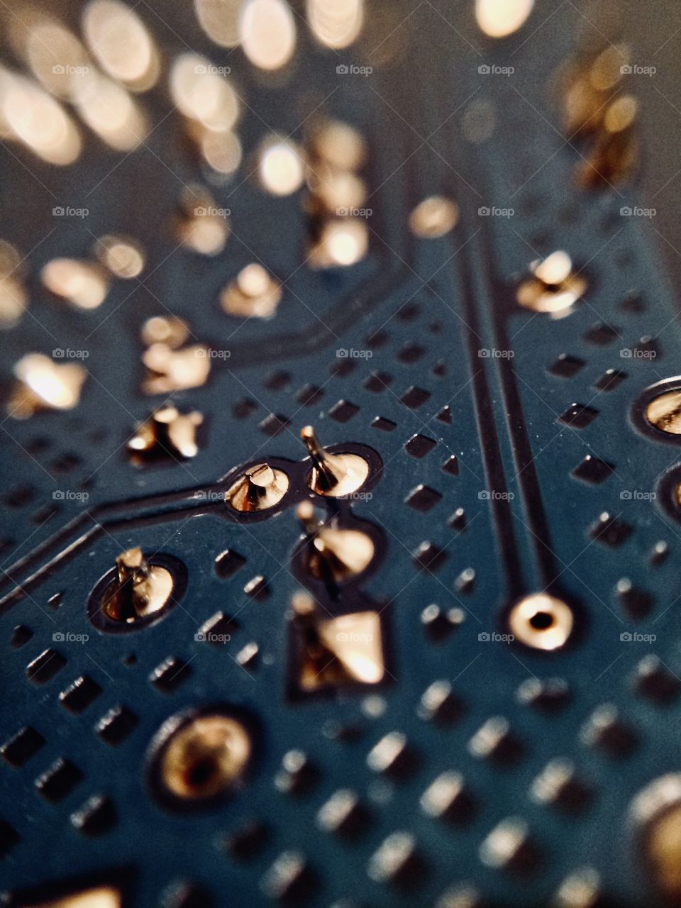 Closeup of a blue printed circuit board with bokeh focus fading into the distance.