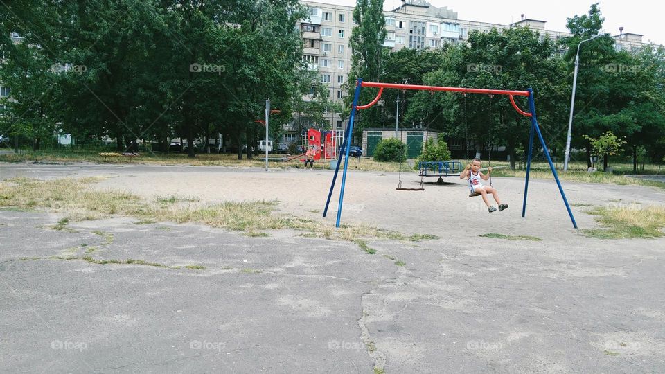 child on the playground riding on a swing