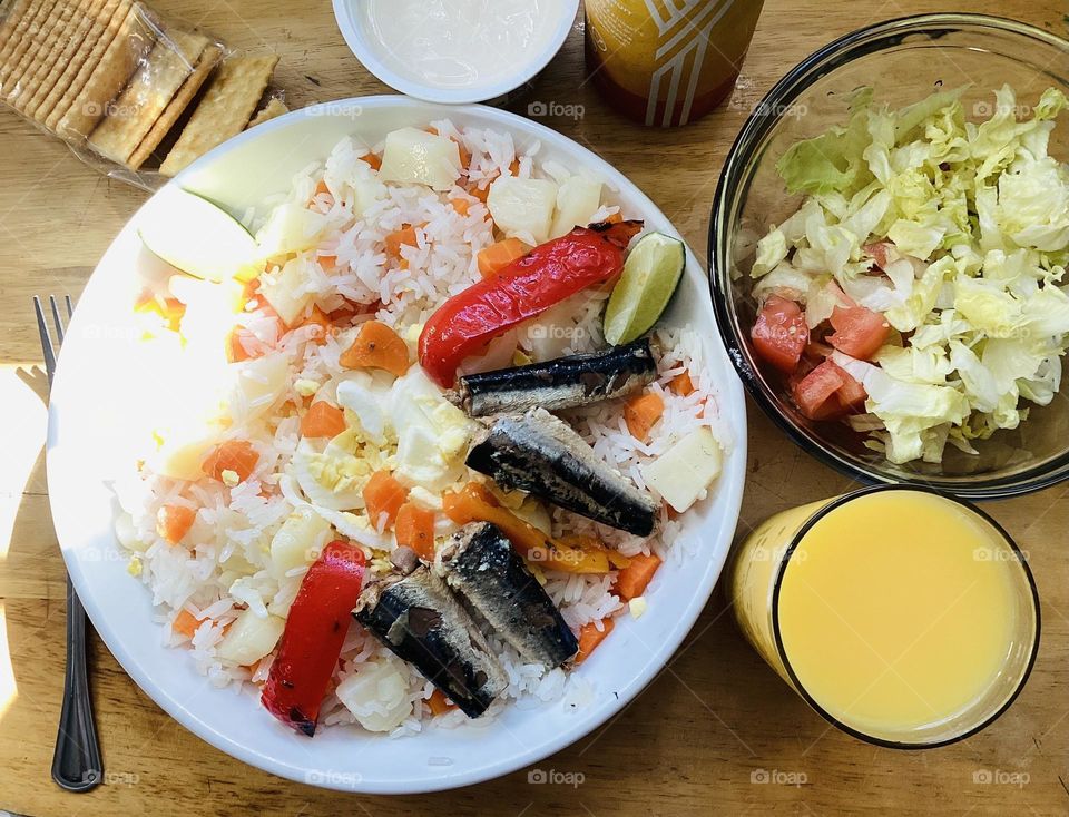 Salad rice whit carrot potatoes sardines ,lettuce and tomato mayonnaise and  orange juice 