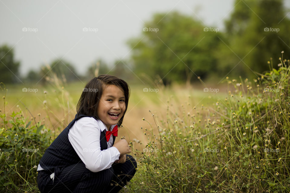 happy smiling young Eurasian boy with long hair wearing costume outdoor in the field