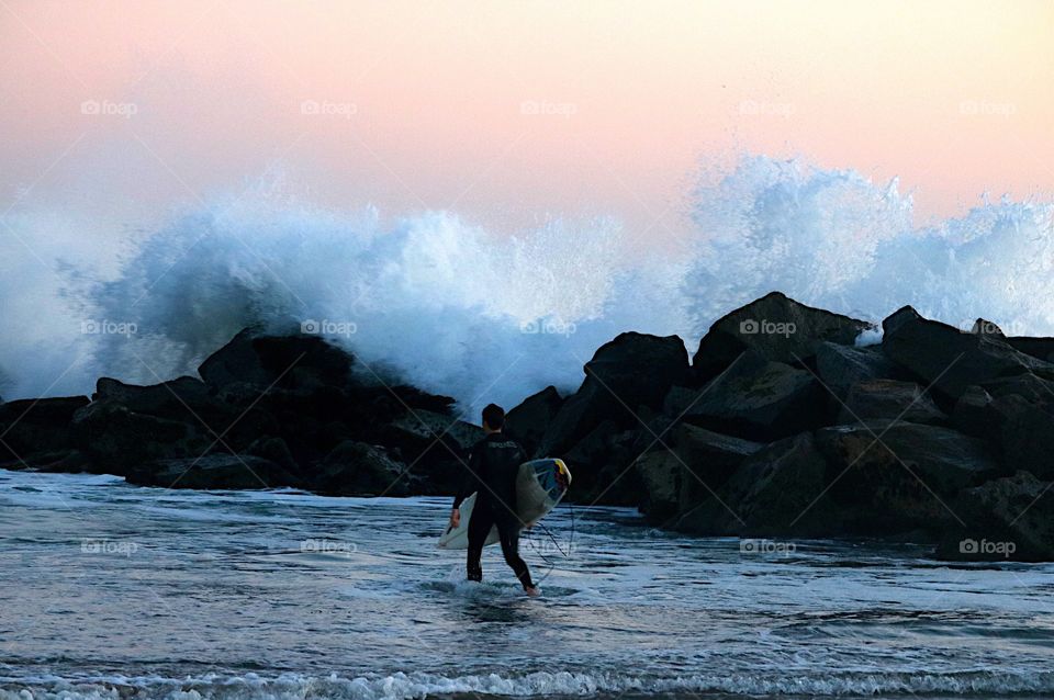 Surfer heading in at sunset.   Venice Beach, CA