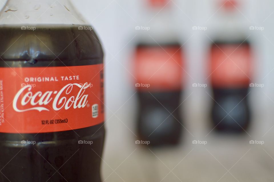 Three plastic bottles of Coca-Cola on a white rustic background
