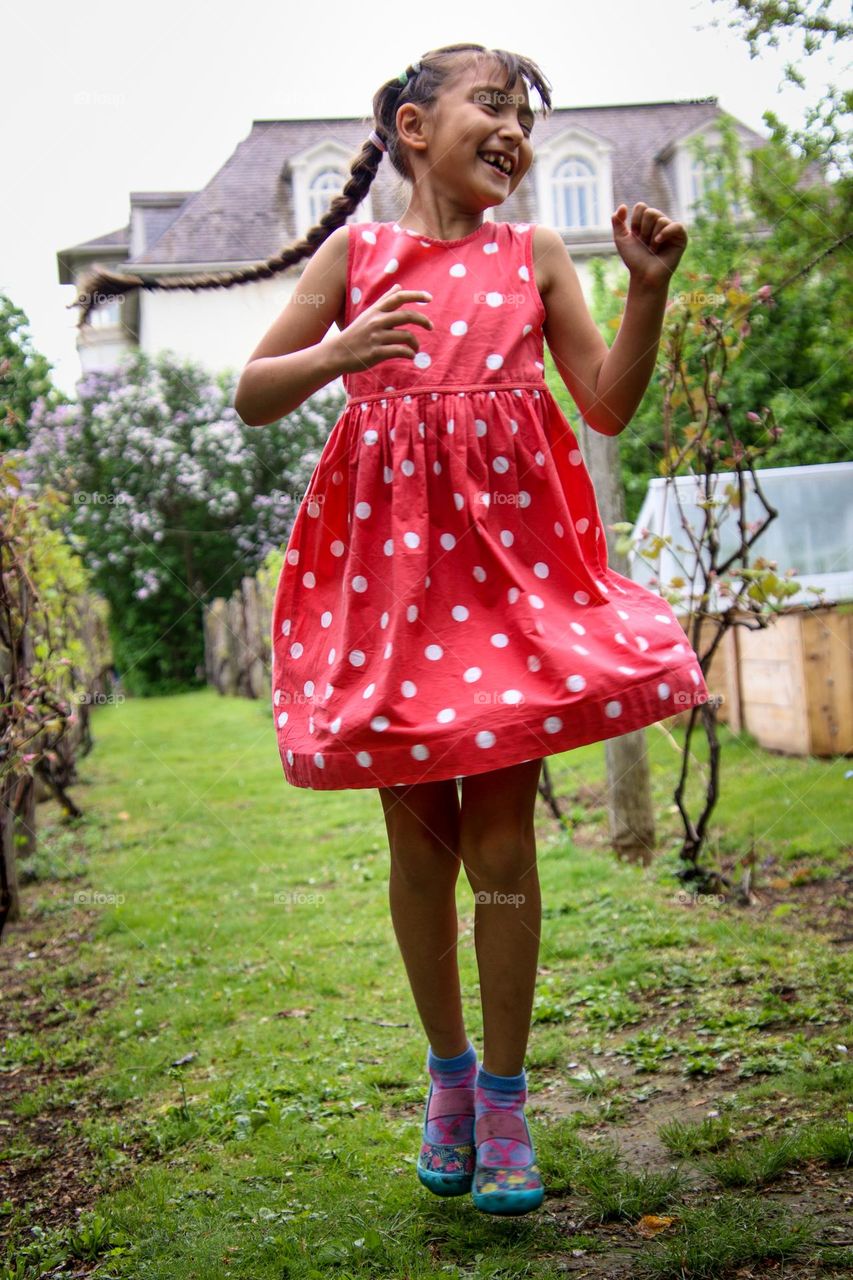 Happy jumping girl in a red polka dot dress