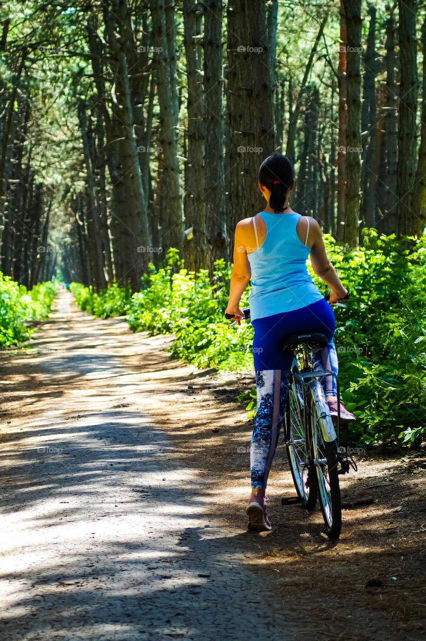 The girl was going to ride a bike through the forest