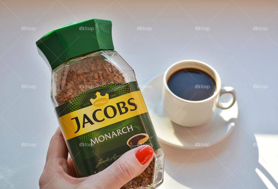 coffee Jacobs in glass bank in the female hand on a white background