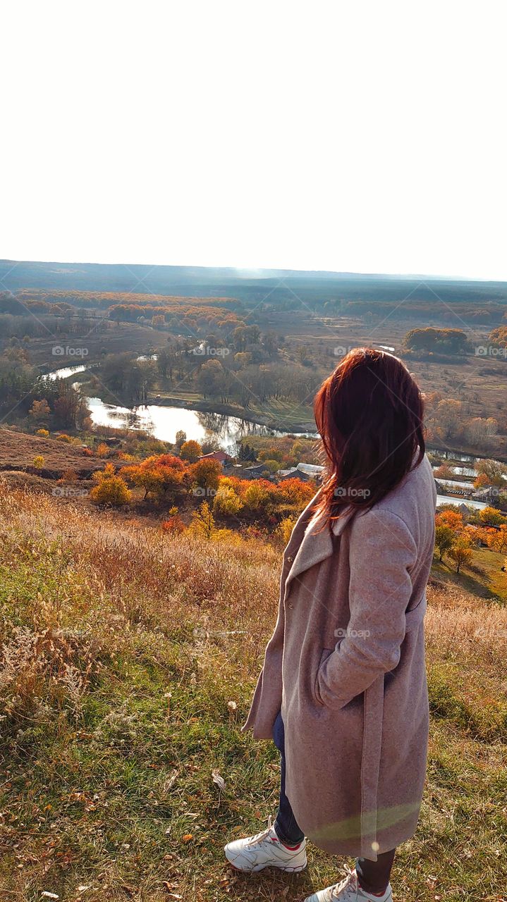 Beautiful coat in autumn style against the backdrop of a beautiful landscape.