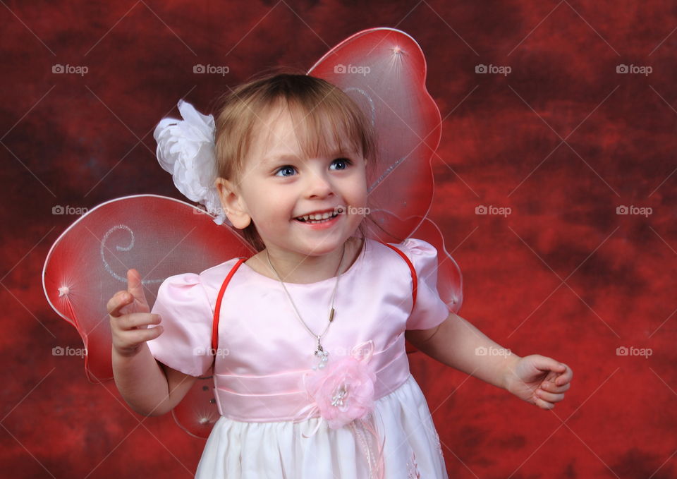 portrait of happy little girl in fairy costume on a red background
