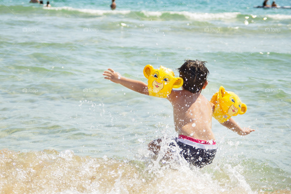 fun in the water. boy having fun on the beach. jumping in the sea