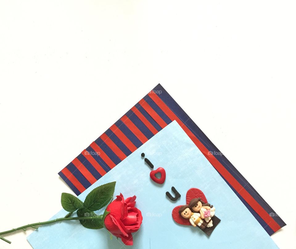 Colored papers and a red rose in white background