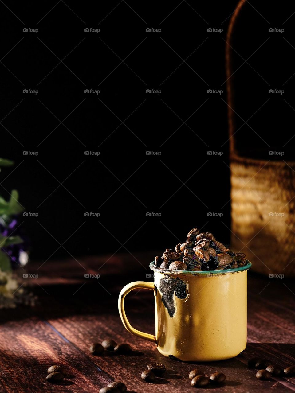 Coffee beans in an iron mug over dark background.