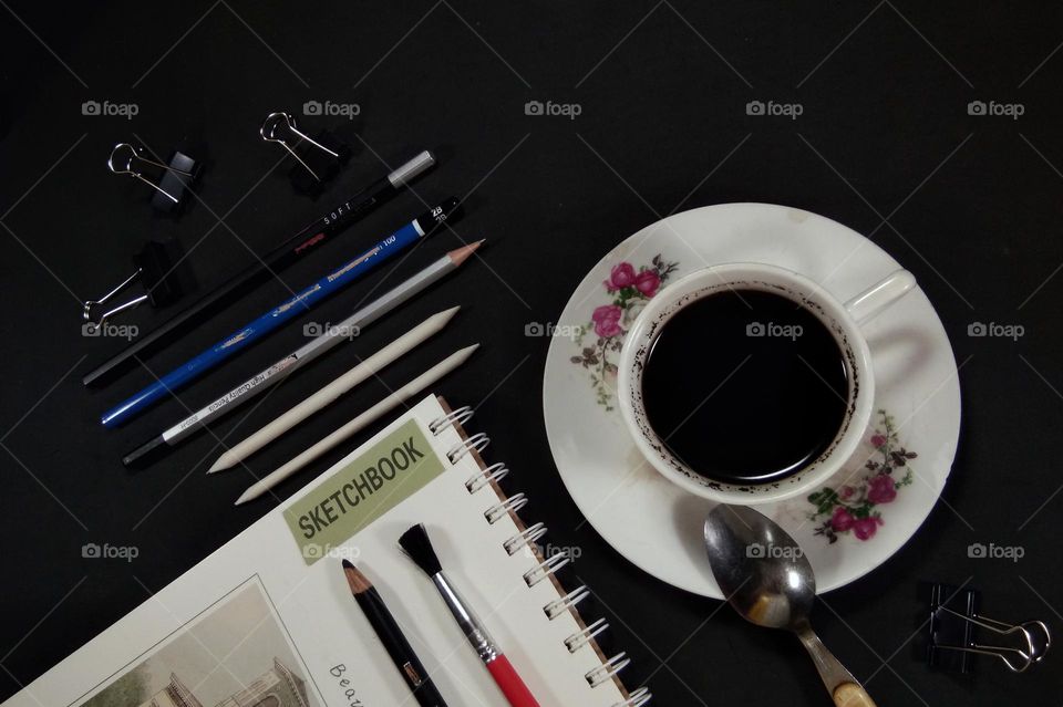 black coffee on the black table with pencil drawings tools. black coffee can be a mood booster when making a creativity