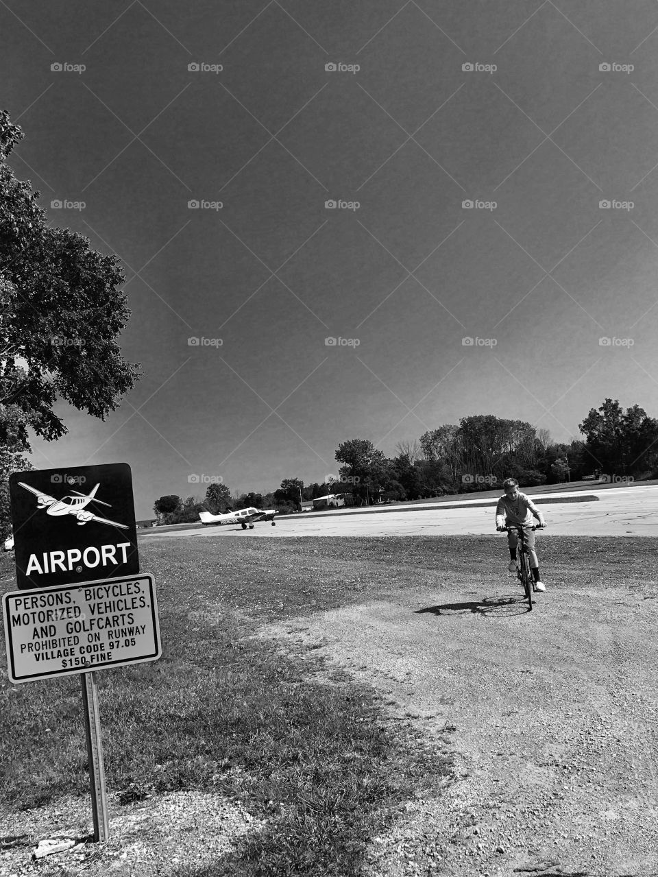 Boy riding bicycle on runway with prohibited sign