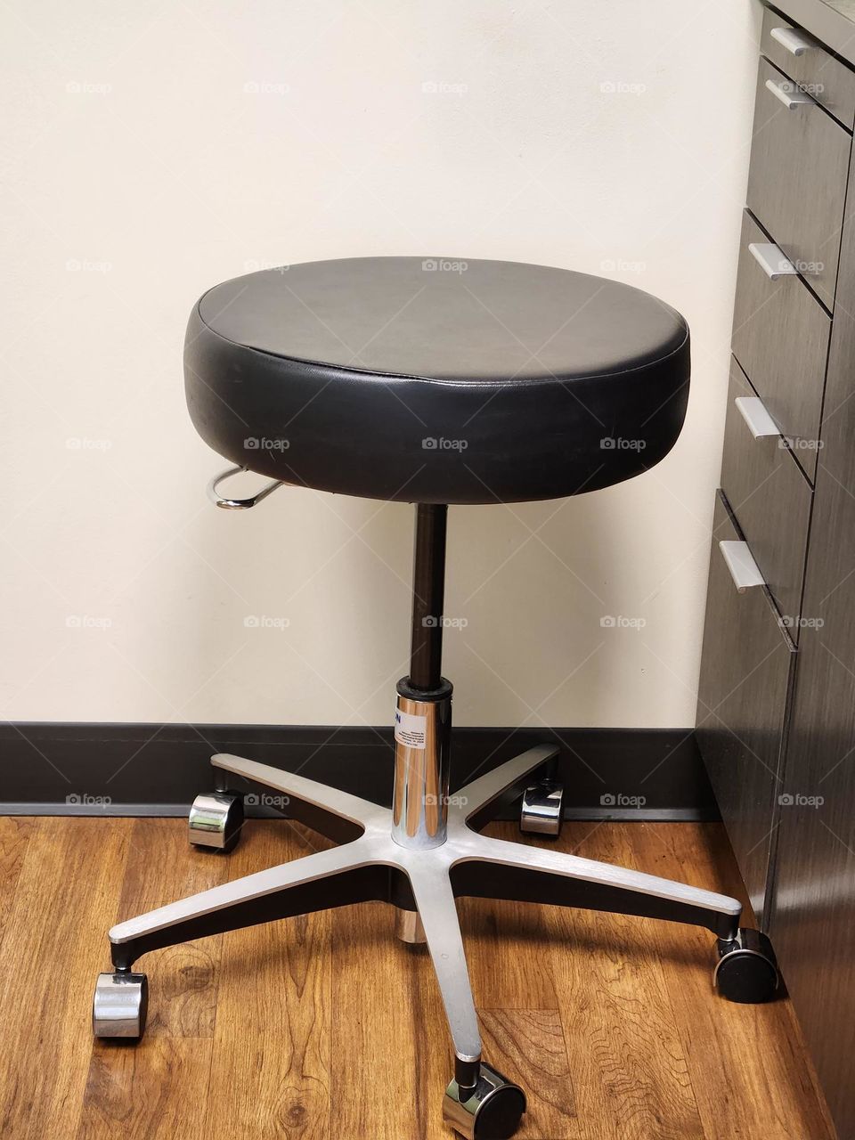 the simple black stool where the doctor will sit for the medical appointment