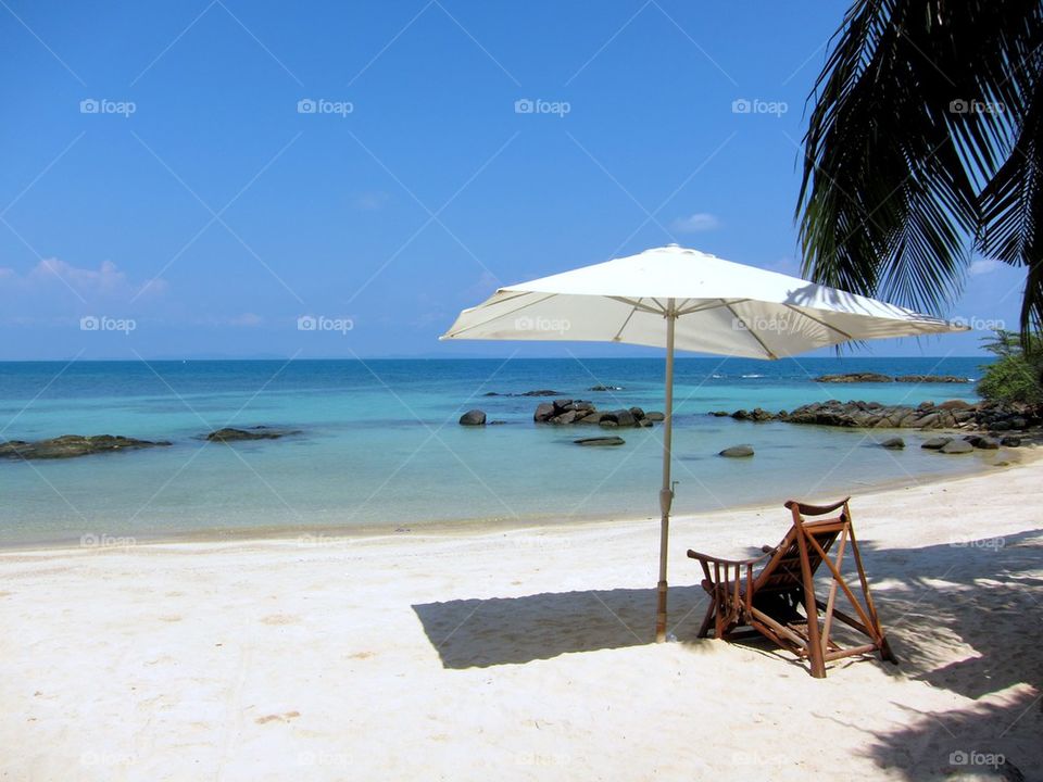 Wooden chair and umbrella on the beach during summer