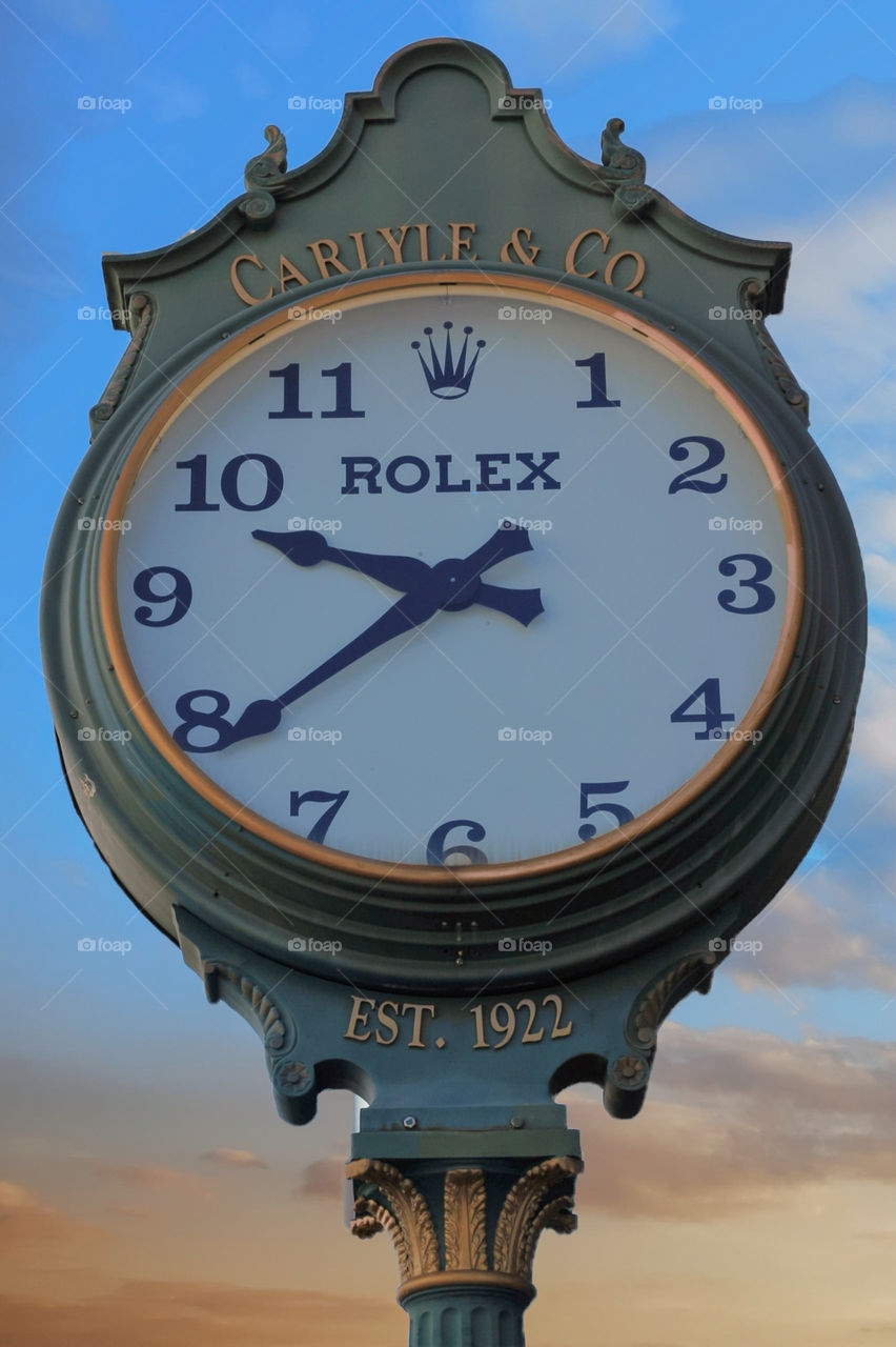 Old Rolex town clock green and gold with clouds and sunset for back drop.