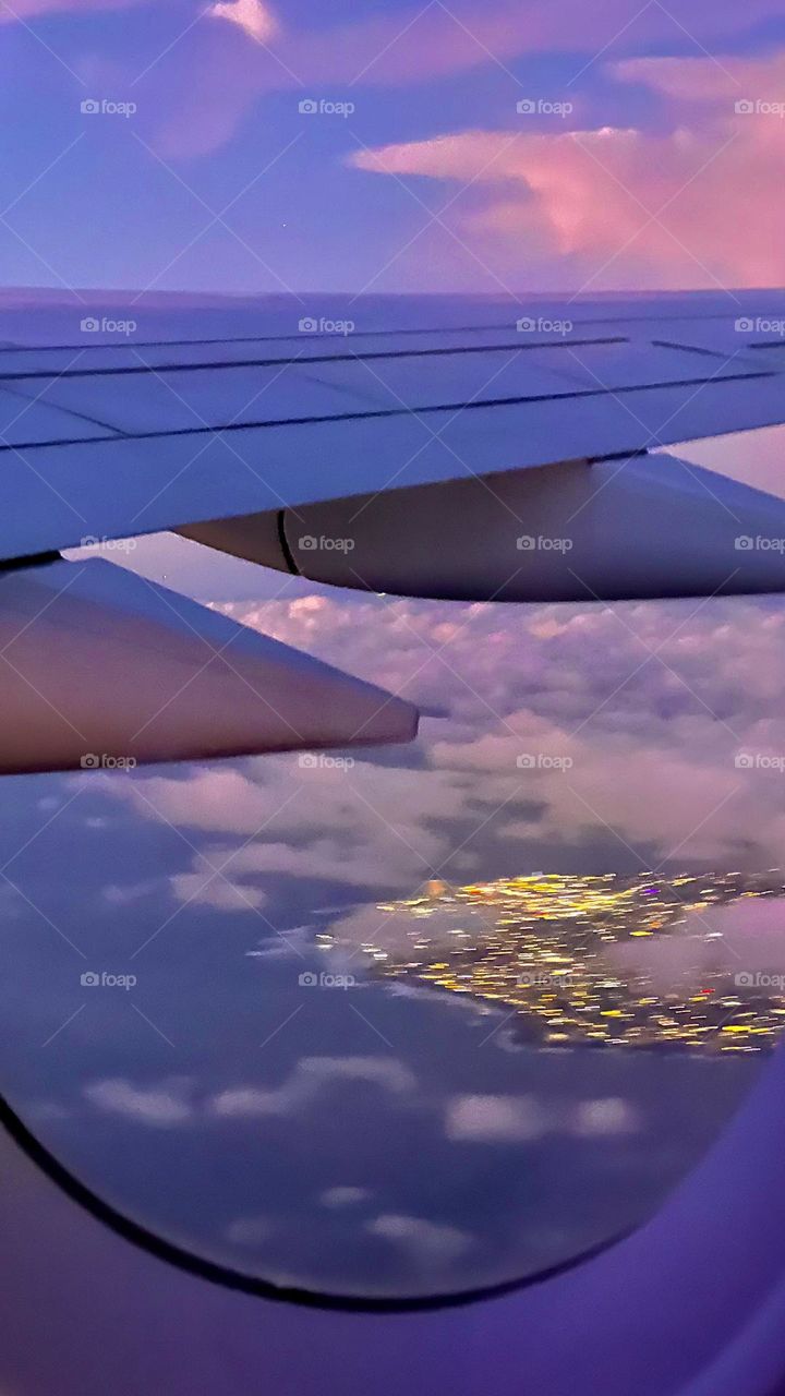 City Lights From Above
City lights flicker below as the plane glides through a dreamy sky painted in violet and gold — a moment of quiet wonder above the world.