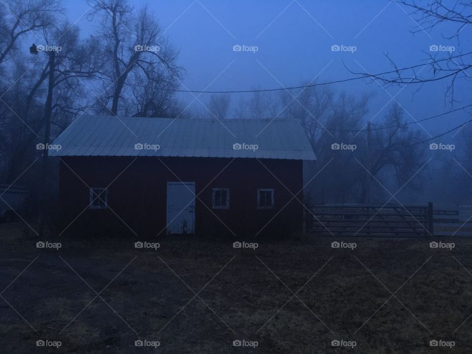 Creepy red barn in a foggy ominous atmosphere.