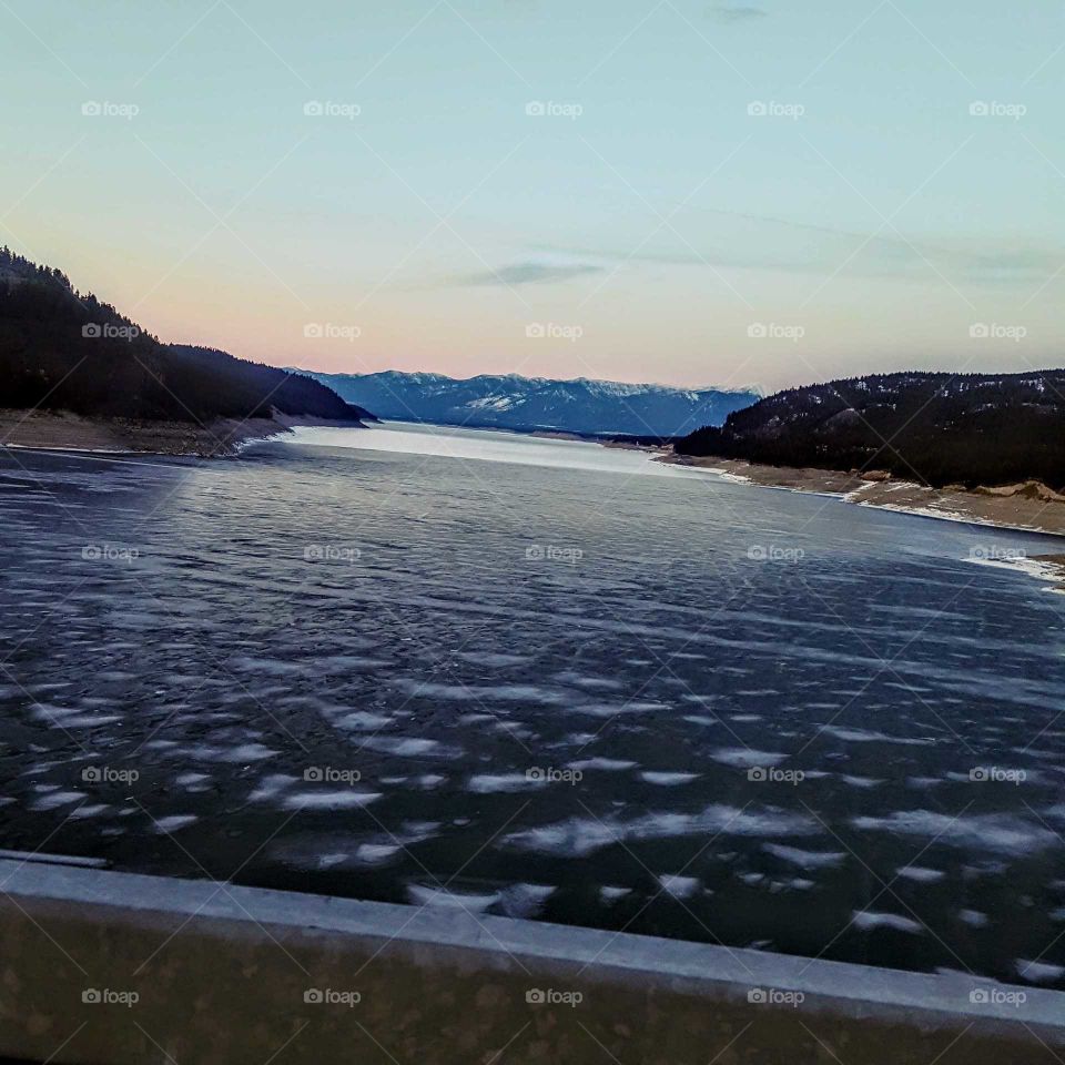 sunset on partially frozen water with mountains