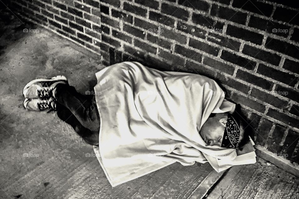 Homeless man asleep on a city street.