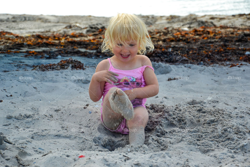 Little girl playing in the sand at Ribban beach in Malmö Sweden. 