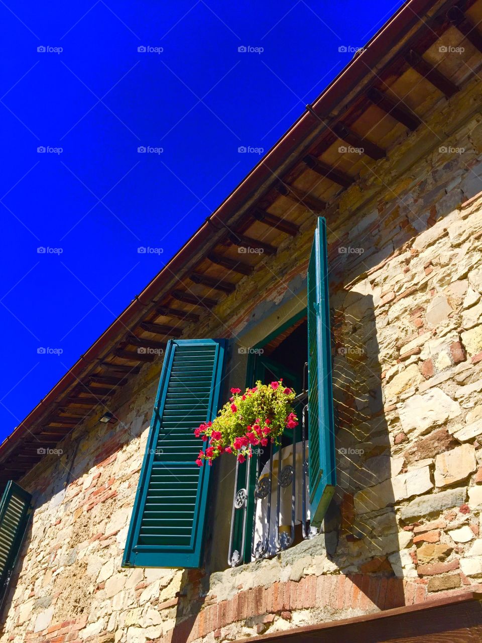 Windows with open wooden shutters and fresh flowers