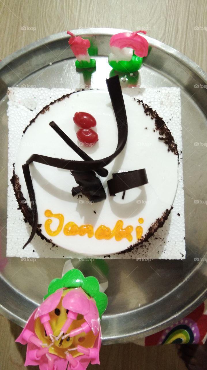 Birthday cake in white colour with chocolate and cherries.