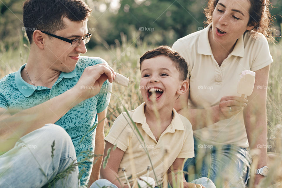 Happy laughing family eating ice cream on a picnic