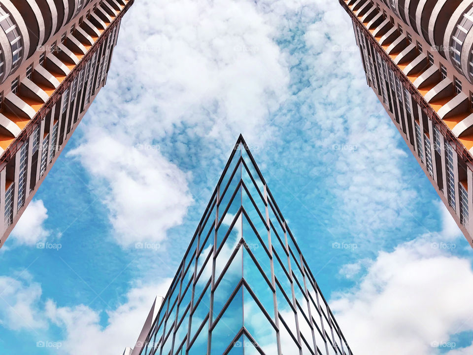 Top view of modern buildings in the city in front of a blue cloudy sky 