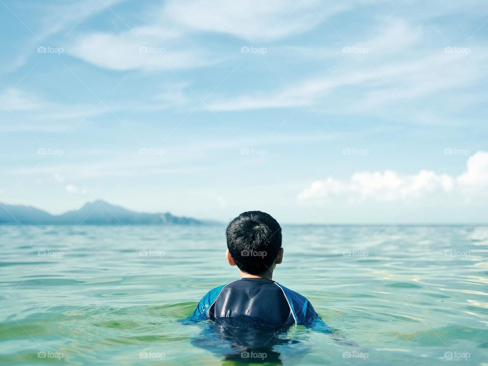 A young boy submerging himself in a calm blue sea in Langkawi, Malaysia