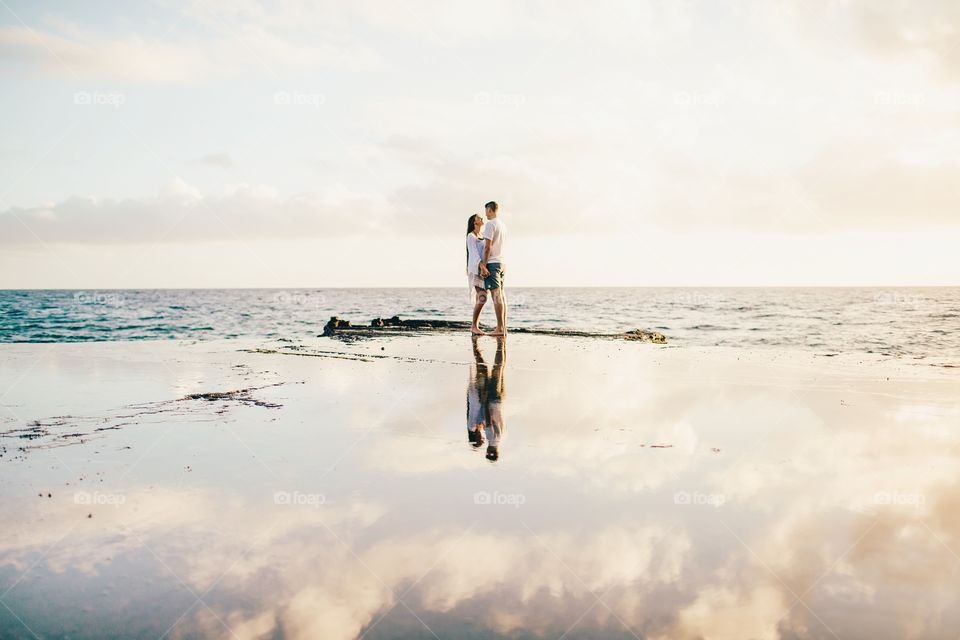 Couple nears the edge to watch the ocean over reflection. 