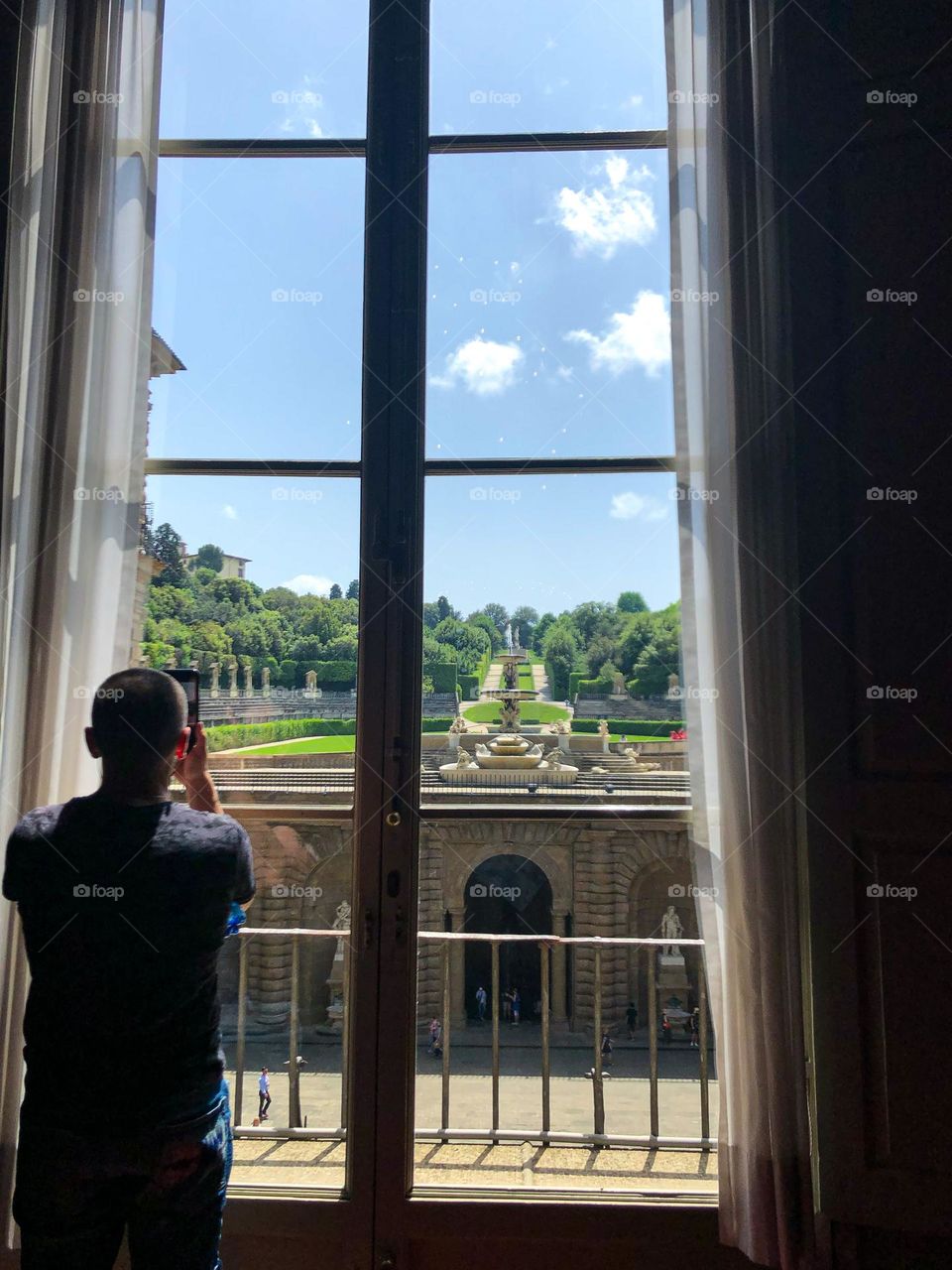 Man takes a picture at the window with tulle of a beautiful view of Florence