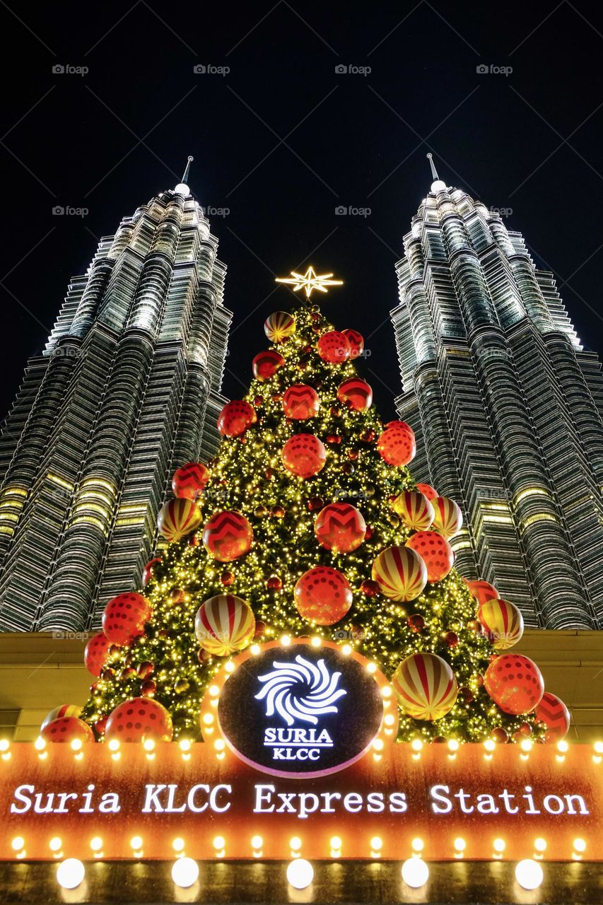 The Petronas twin towers shine with giant Christmas Tree in the middle in the Kuala Lumpur City Center (KLCC) Malaysia