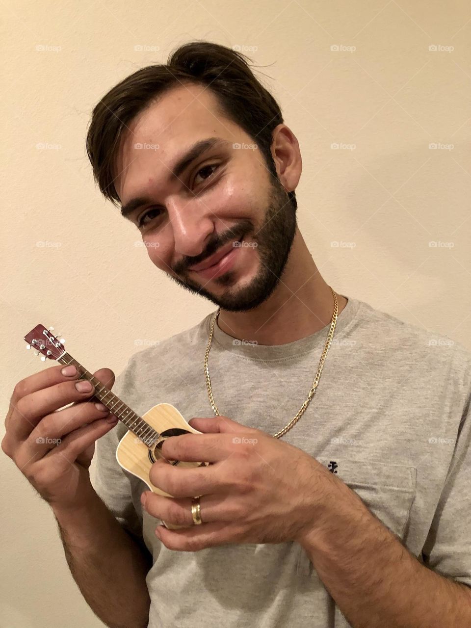 Young bearded man showcasing decorative mini guitar