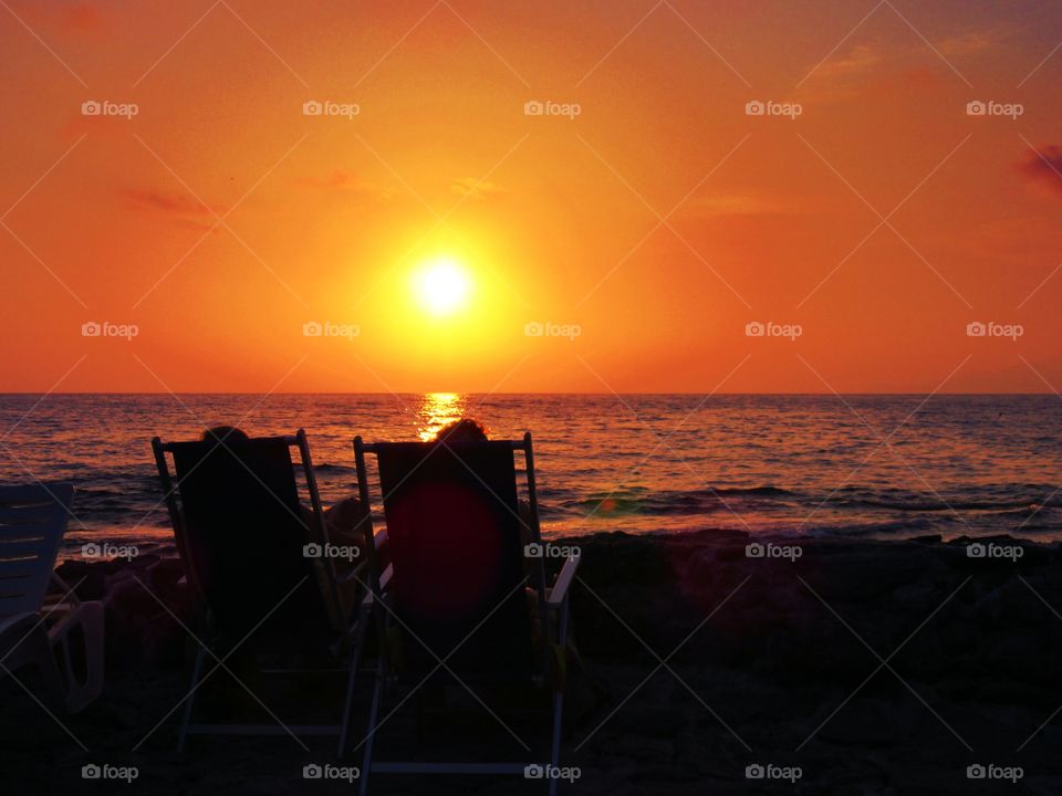 People resting on beach during sunset