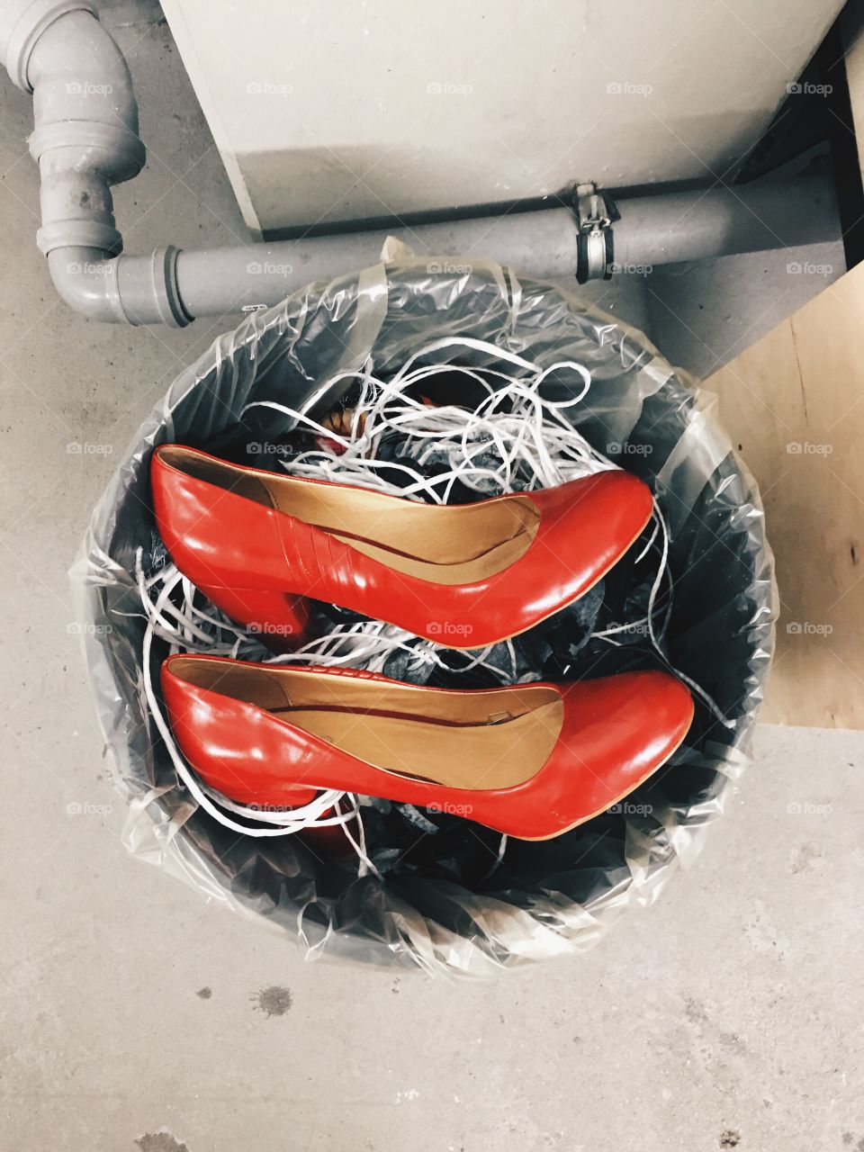 Top down shot of a red pair of high heels in a trashcan